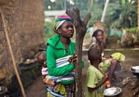In this photo taken Sunday Nov. 23, 2014, women gather  in the Guinean village of Meliandou, some 400 miles (600 kms) south-east of Conakry, Guinea, believed to be Ebola's ground zero. In Meliandou, as in many other villages across Ebola country, the disease is shrouded in mystery, surrounded by suspicion and rumors. People here still believe that Ebola was disseminated by white people seeking the deaths of blacks, including through a measles vaccination campaign; by a laboratory testing bats to create a vaccination against the virus; by politicians from a rival tribe bent on killing off the forest people; by white miners looking to exploit a nearby mountain of iron ore. (AP Photo/Jerome Delay)